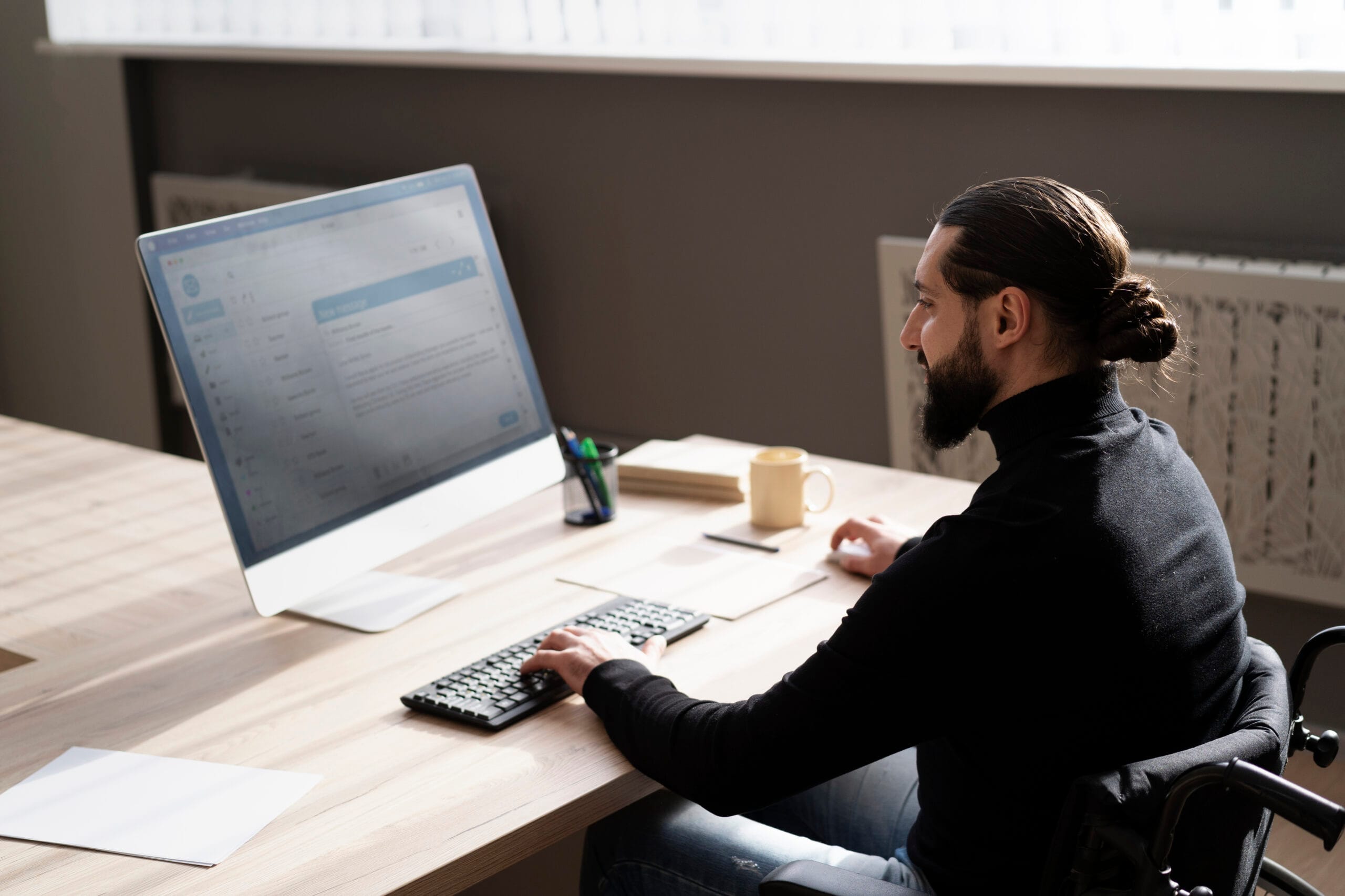 Professional man in a wheelchair using computer to write a resume with help from an AI resume objective generator