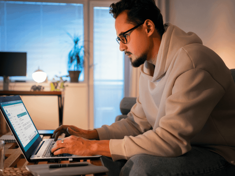 Man working from home on a laptop at night, searching for online AI jobs no experience in 2025.