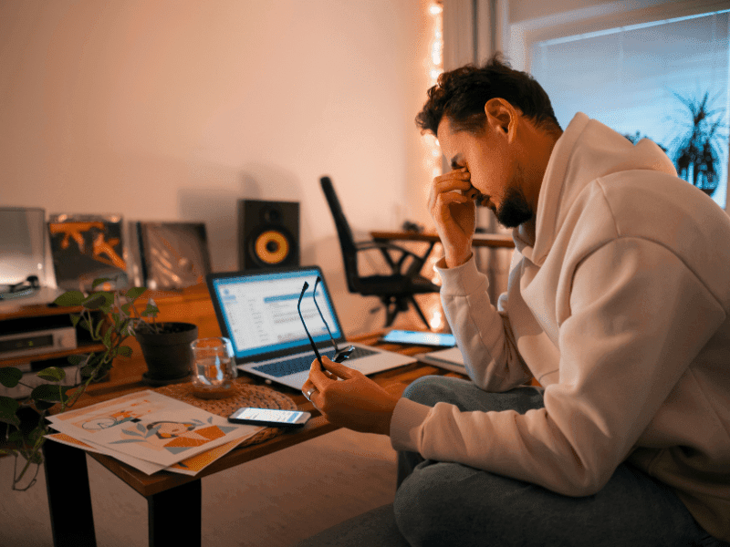 Frustrated job seeker exploring AI Resume Builder Reddit tools on a laptop in a modern home office setup.