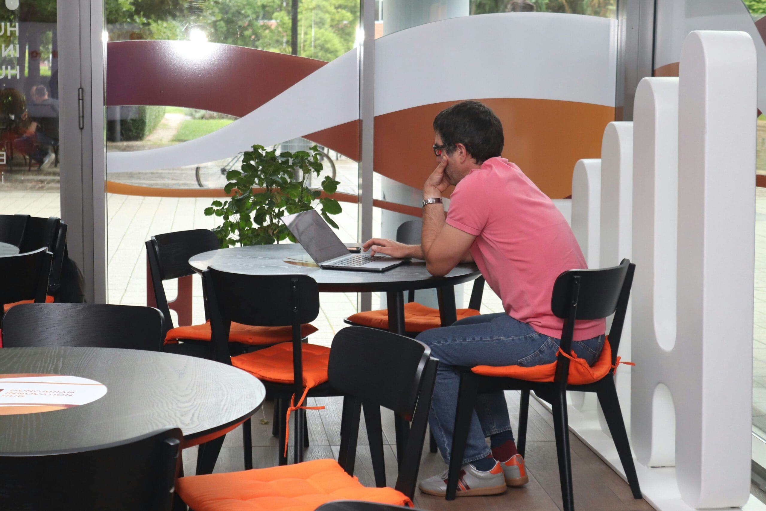 A person searching for AI jobs for beginners on a laptop in a cafe, highlighting the remote and freelance AI teaching opportunities available online.