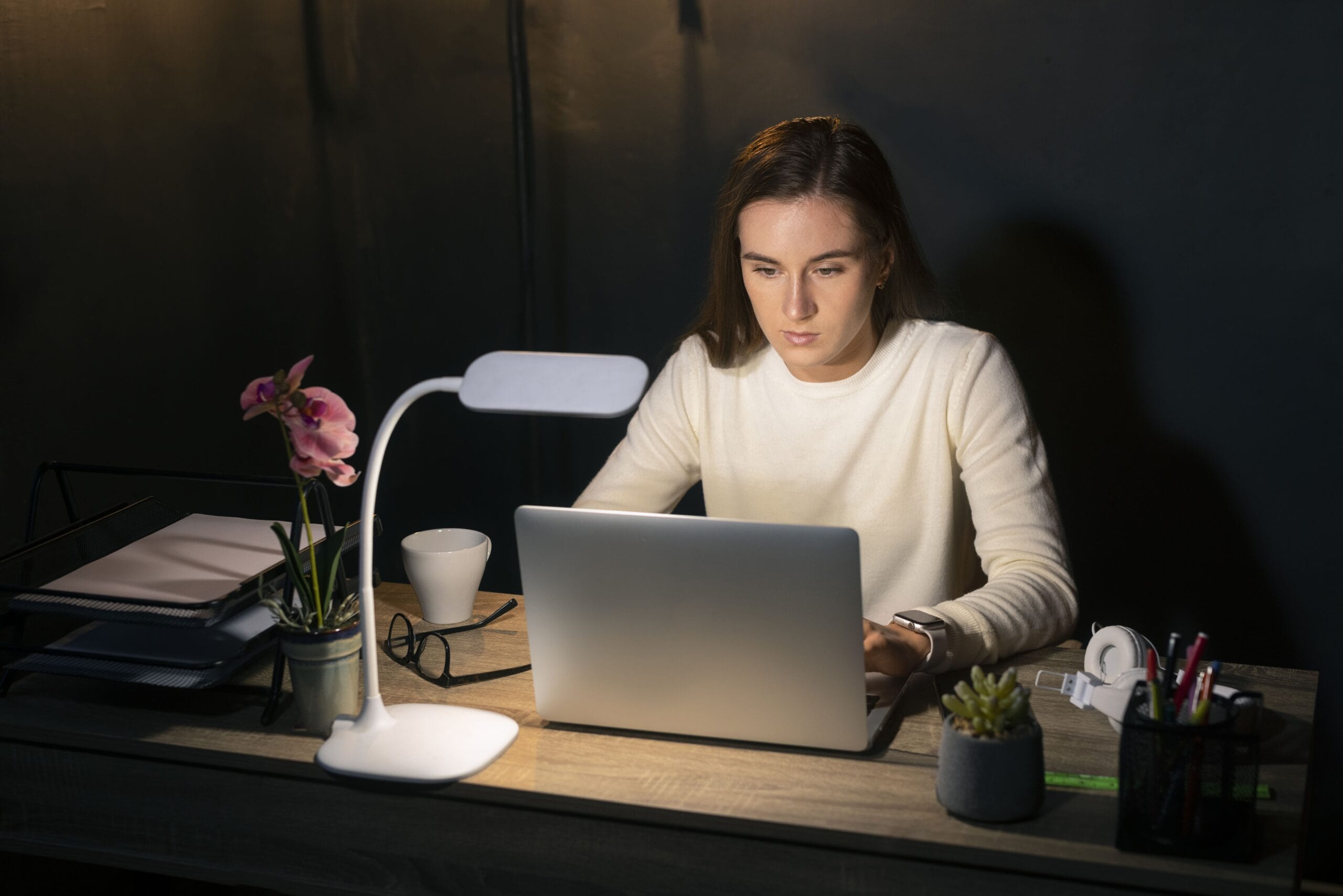 A focused young professional working late at her desk with a laptop, creating her resume using AI tools — representing the Best AI for Resume Reddit users trust.